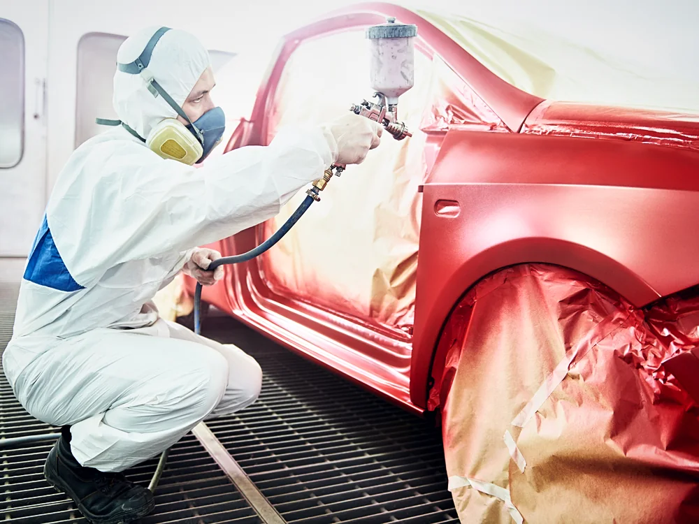 A refinisher spraying a panel in the booth